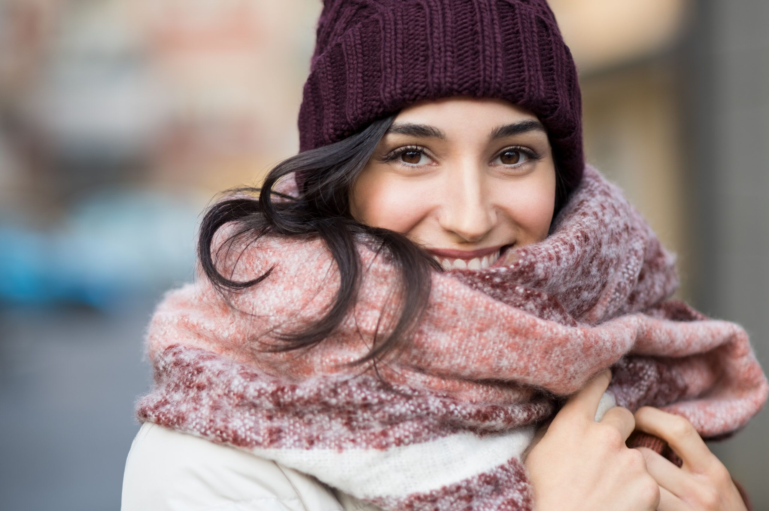 Giovane donna sorridente avvolta in sciarpa rosa. indossa un berretto a contrasto